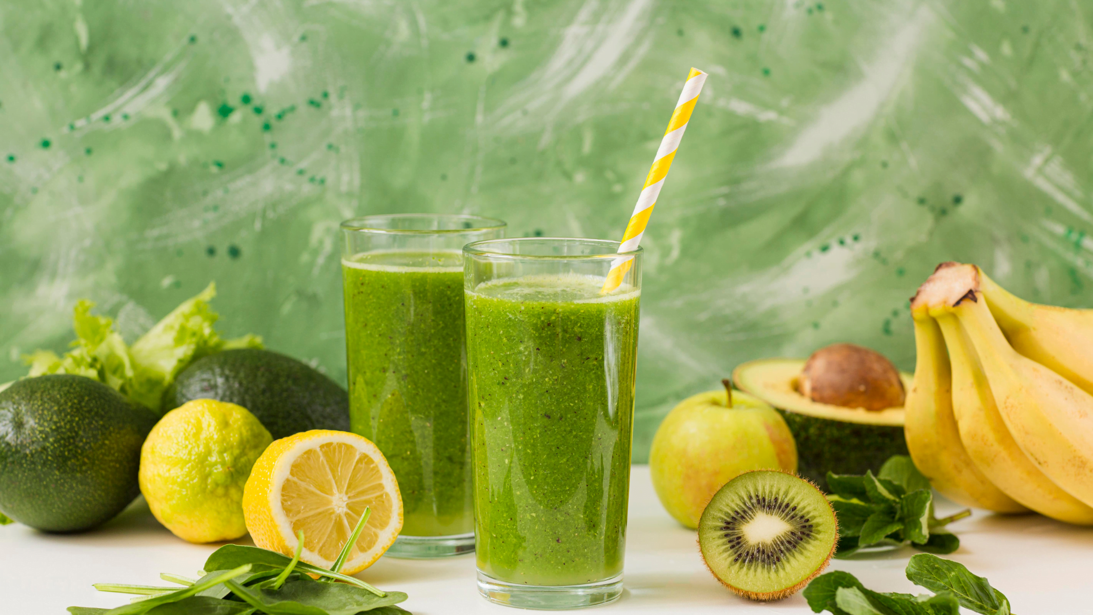 2 glasses of green smoothies with some fruits