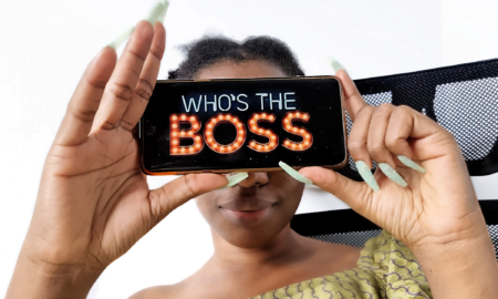 African girl holding a phone with the inscription of Nollywood movie on Netflix, who's the boss- a movie on impostor syndrome